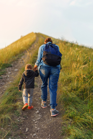 Mother and son went up the hill. Autumn evening. Camping, Travel Family Concept. Mountain climbing.の写真素材