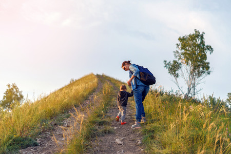 Mother and son climb up the hill. Autumn evening. Camping, Travel Family Concept. Mountain climbing.の写真素材