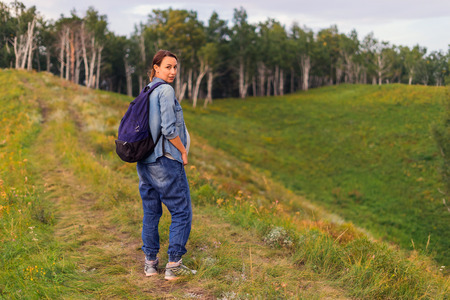 Woman walks on the hills and forests, a traveler with a backpack walking along the path in the woods. A pregnant woman is resting in natureの写真素材