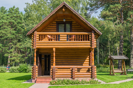 Garden house in the woods. Cottage with a balcony, Swing in the meadow. Wooden house, grass, flowers.の写真素材
