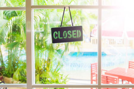 The Â«closedÂ» label hangs on the window. Sunny summer day, the door with a window.の写真素材