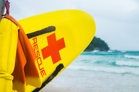 Rescue board and vest hang on a pole on the beach. Beach savers. Red cross on the sea coastの写真素材
