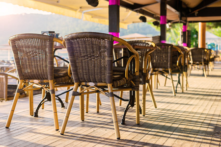 Veranda with chairs. Cafe on the beach. Wicker furniture. Empty restaurant. Light in a cafe.のeditorial素材