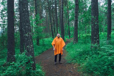 A man in a raincoat in the forest. A man walks through the forest rainy dayの写真素材
