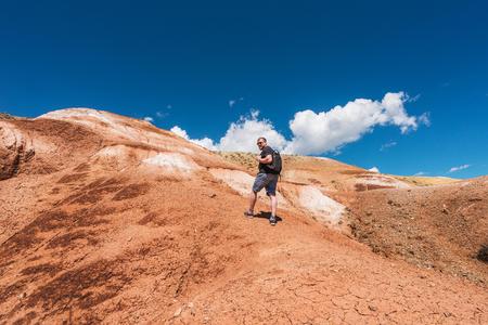 Tourist with a backpack climbs the mountain. Red Mountain Mars in Altai. Man on the hill