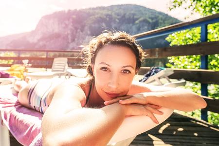 The girl sunbathes by the pool. The girl in a bathing suit lying on a lounger on a sunny day.