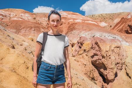 Tourist girl with a backpack on top of a mountain. Red mountains in the Altai. Traveler in the...