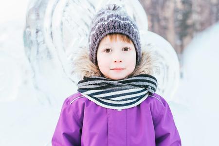 A boy in winter clothes at the ice sculptures. Machchik walks in the winter in the park, a snowy town.の写真素材