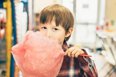 The boy eats cotton candy. A child holds a cotton wool on a stick. holiday treat.の写真素材