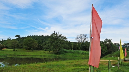 Pink and yellow flag with green natural grass land and blue sky backgroundの写真素材