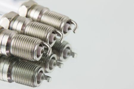 three new automotive spark plugs on a mirror backgroundの写真素材