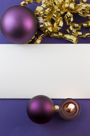 blank Christmas card with purple baubles, gold curly ribbon, tea light candle and copyspaceの写真素材