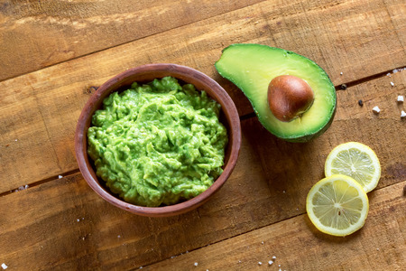 guacamole and ingredients - avocado, lemon, pepper, salt on the wooden dark table top viewの写真素材
