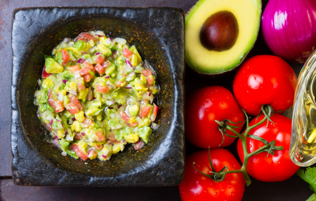 Guacamole - latin american mexican sauce in stone mortar and ingredients on dark background. Top viewの写真素材