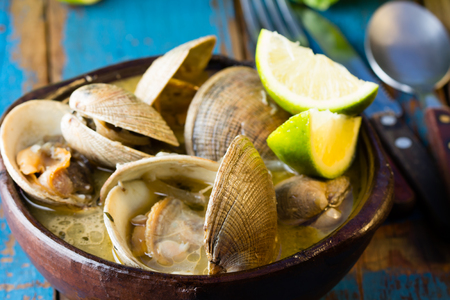 Seafood soup of clams in clay bowl on wooden blue background.  Mariscal or paila marinaの写真素材