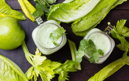 Two glasses of green smoothie and fresh green vegetables and fruits on black background. Top viewの写真素材