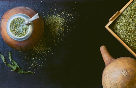 Yerba mate in calabash and dry herb in clay bowl on black background. Top viewの写真素材