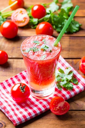 Tomato smoothie, fresh tomatoes and cilantro on wooden dark backgroundの写真素材