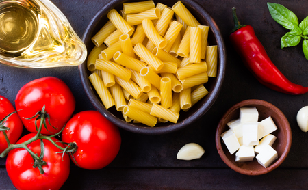 Pasta. Ingredients for italian food - salad wish pasta and vegetables - dry penne ,olive oil, basil, garlic, tomatoes, basil, black pepper, cheese. Top viewの写真素材
