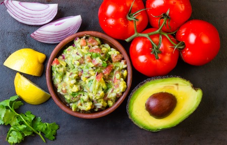 Guacamole and ingredients - avocado, tomatoes, onion, cilantro dark background. Top viewの写真素材