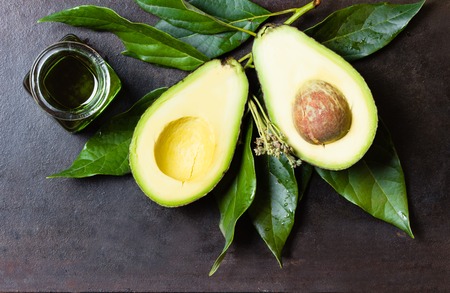 Avocado with leaves and jar of green avocado oil on black background. Top viewの写真素材