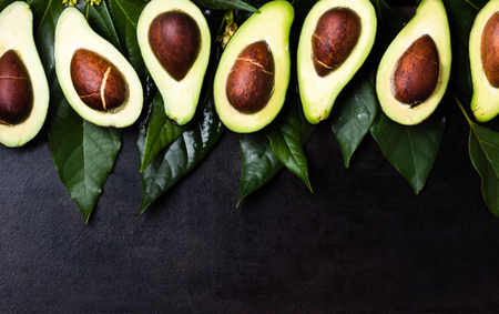 Fresh avocado palta with leaves on black background. Vegetarian or healthy eating. Healthy fatの写真素材