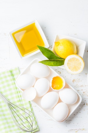 Ingredients for sauce mayonnaise eggs, lemon olive oil on white background. Top view