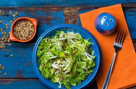 Vegetarian salad with lettuce and lentil on blue plate. Colorful blue orange background. Healthy foodの写真素材