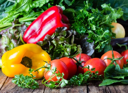 Fresh vegetables. Red and llelow bell pepper, celery tomatoes parsleyspinach mangold on wooden rustic backgroundの写真素材