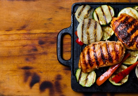 Barbecue grilled chicken and vegetables on wooden background. Top viewの写真素材