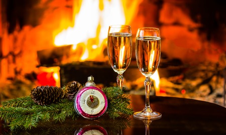 Two glasses of sparkling white wine and New Year Christmas decoration in front of warm fireplace. Romantic, cozy relaxed magical atmosphere near fire. New Year or Christmas conceptの写真素材