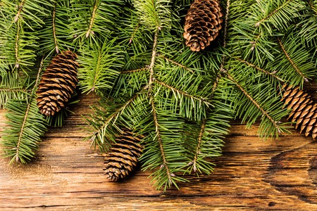Christmas New Year background. Christmas tree branches. Fir tree branches and fir cones on wooden rustic background. Top view, copy spaceの写真素材