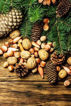 Christmas composition. Fir tree, pine tree branches, pine cones, fir cones, nuts, walnuts pine nuts hazelnuts almond. Christmas tree on wooden backgroundの写真素材