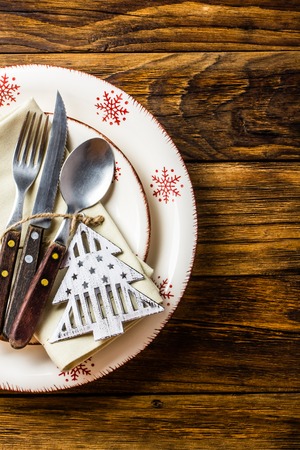 Christmas table setting. Plates, spoon fork knife, Christmas decoration on wooden background. Christmas background. Top viewの写真素材