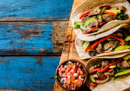 Mexican pork tacos with vegetables and salsa. Tacos al pastor on wooden blue rustic background. Top view. Copy spaceの写真素材