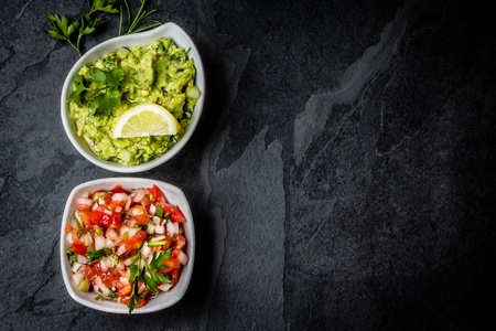 Traditional mexican Latin American sauces - avocado sauce Guacamole, tomato sauce Salsa in white bowls on stone slate backgroundの写真素材