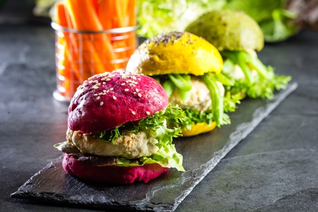 Colored green, yellow and purple burgers on slate board, slate backgroundの写真素材