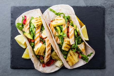 Mexican chicken tacos with grilled pineapple on slate board, slate gray backgroundの写真素材