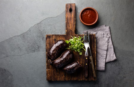 Bloody sausages - prieta on wooden board with chili sauce, slate backgroundの写真素材