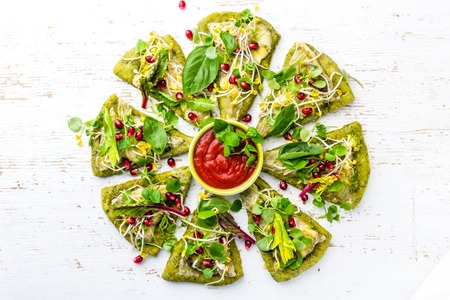 Green spinach dough, vegetables and cheese pizza on wite backgroundの写真素材