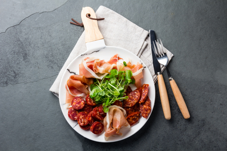 Spanish ham serrano and salami on white marbled plate. Top view.の写真素材