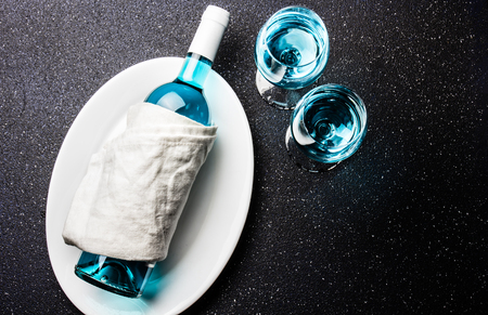 Bottle and two glasses of trendy blue wine. Spanish blue wine chardonnay on black background. Fancy wine, top view.の写真素材