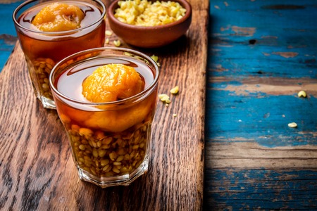 Mote con huesillo. Traditional Chilean drink made from cooked husked wheat and dried peach on wooden...