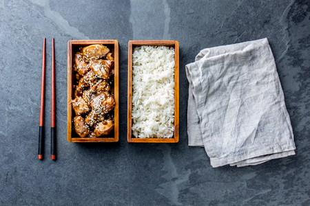 Japanese food. Chicken teriyaki with rice in wooden bento lunch box. slate background, top viewの写真素材