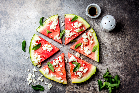 Fresh watermelon pizza salad with feta cheese, mint, salt and oil on stone background.の写真素材