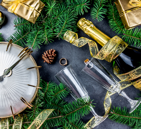 New Year Eve tradition rutual put gold ring to champagne. Spanish and Latin American New year traditions. Two champagne grasses, bottle of champagne, vintage clock and Christmas decorations Top view.の写真素材