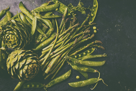 food background with fresh green vegetables - asparagus, artichoke and green pea. Toned photo.の写真素材