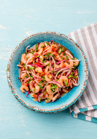 Ecuadorian shrimps ceviche sebiche with tomatoes in blue bowl, wooden blue background. Traditional ecuadorian colombian or mexican dish.の写真素材