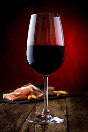 Glass of red wine and bord with ham serrano. Close upの写真素材