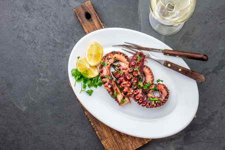 Grilled octopus on white plate serverd with white wine , top view. Seafoodの写真素材